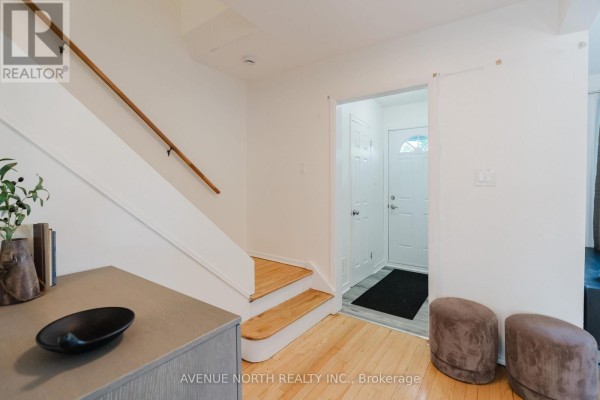 Interior entryway with light wood floors, a staircase, a grey console table with decorative items, and a view of the front door. - 2732-2730 Colman Street, Ottawa