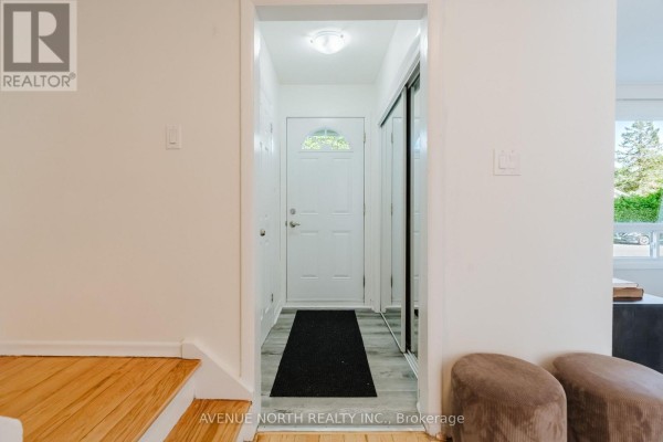 Interior entryway with light wood floors, a grey console table, and a white front door with glass panes and a black mat. - 2732-2730 Colman Street, Ottawa
