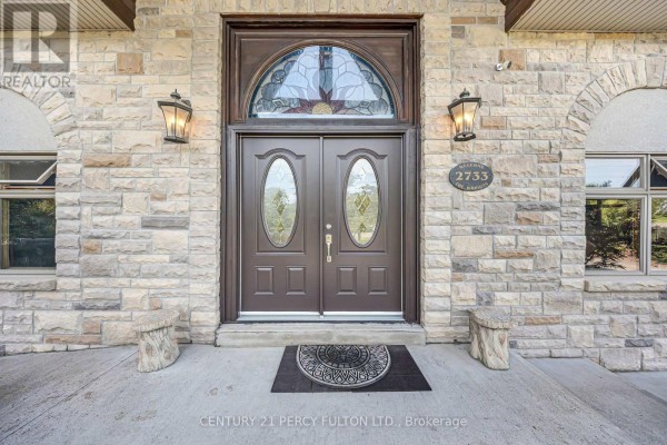 Aerial view of the property showcasing the stone house and surrounding greenery. - 2733 Taunton Road, Clarington