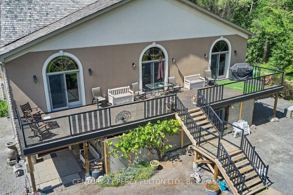 Side view of the house with gardens, trees, and a detached garage in the background. - 2733 Taunton Road, Clarington