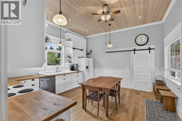 Kitchen with white cabinets, butcher block counters, and a wooden table with chairs. - 2737 Derwent Ave, Cumberland