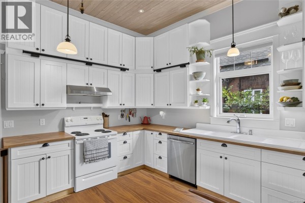 Corner view of a white kitchen with stainless steel appliances and a window. - 2737 Derwent Ave, Cumberland