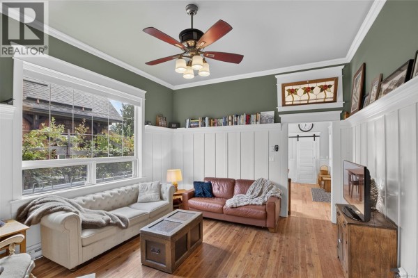 Living room with a large window, green walls, white wainscoting, and two sofas. - 2737 Derwent Ave, Cumberland
