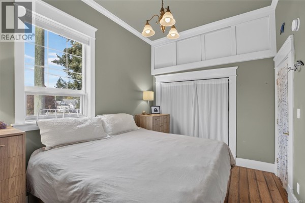 Bedroom with a large window, a bed, and a wooden dresser against a green wall. - 2737 Derwent Ave, Cumberland