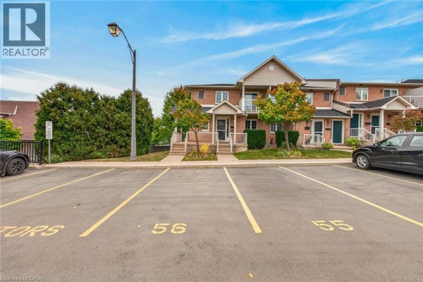 Parking lot view facing the front of brick townhouses on a slightly elevated lot. - 2737 King Street E Unit# 55, Hamilton