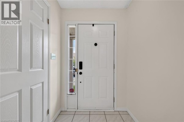 Interior view of a white front door in a hallway with tiled flooring. - 2737 King Street E Unit# 55, Hamilton