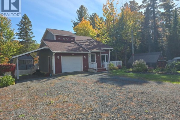 Side view of a red house with a garage and a covered carport with a screened room. - 2737 Middle River Rd, Middle River