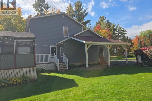 Side and back view of a blue house with a covered porch and a screened porch. - 2737 Middle River Rd, Middle River
