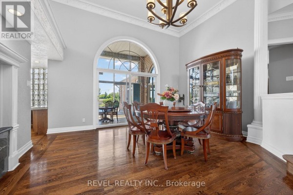 Dining room with hardwood floors, round wooden table, chairs, and glass display cabinet. - 2738 Lower Base Line, Milton