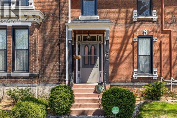 Close-up of the front entrance with a gray door, transom window, and red brick facade. - 274 Crawford Avenue, Windsor