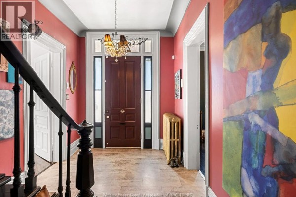 Interior foyer with red walls, wood staircase, tiled floor, and a chandelier above the door. - 274 Crawford Avenue, Windsor