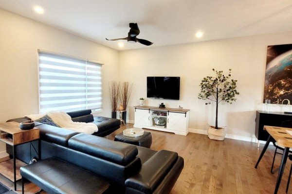 Open concept living space with a black leather sectional, entertainment unit, and dining table. - 274 Roxanne Street, Clarence Rockland
