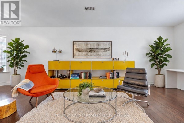 Living room with orange and black chairs, glass coffee table, and yellow storage unit. - 274 Wallace Avenue, Toronto