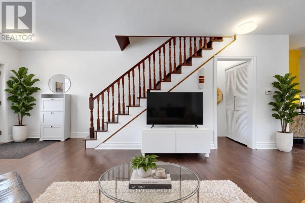 Living room featuring a wooden staircase, television, and white storage unit. - 274 Wallace Avenue, Toronto