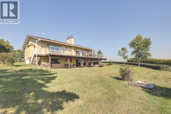 Concrete patio with a stone picnic table, red Adirondack chairs, and garden landscaping. - 274133 Range Rd. 252, Rural Rocky View County