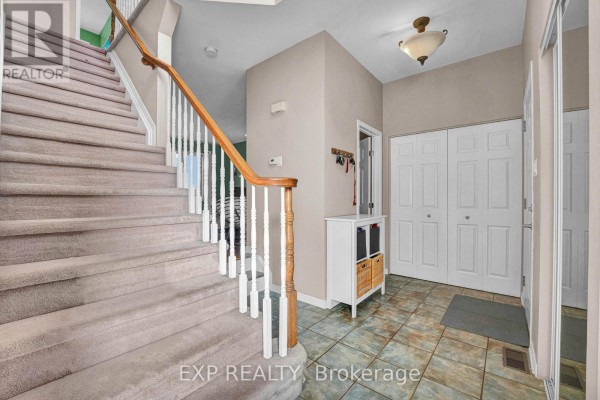Interior foyer with a carpeted staircase, tile flooring, and double closet doors. - 2744 Sylvain Street, Clarence Rockland