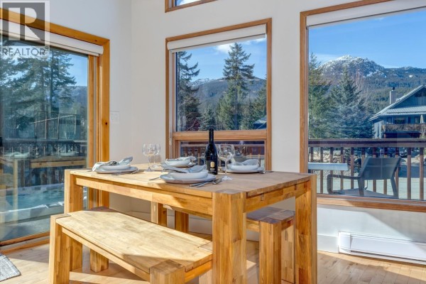 Living room with white sofas, wood stove, and large windows. - 2748 Coyote Place, Whistler