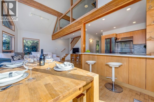 Living room with white sectional, wood stove, and mountain views. - 2748 Coyote Place, Whistler