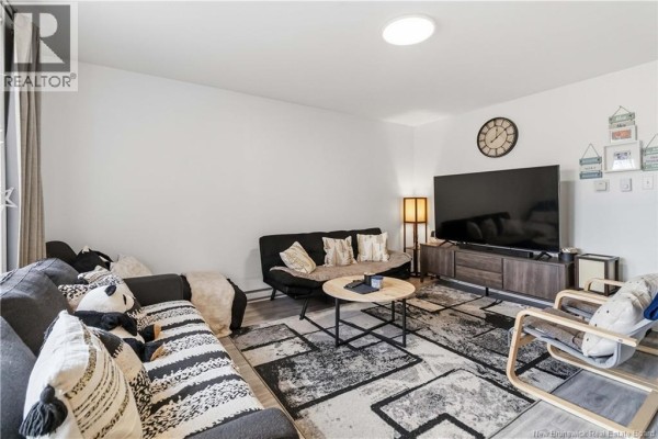 Living room with sectional sofa, futon, coffee table, and television on stand. - 275-279 Ayer, Moncton