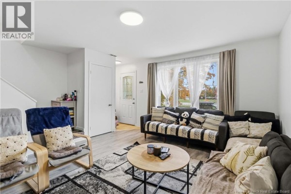 Living room with sofas, chairs, coffee table, and doorway to entrance. - 275-279 Ayer, Moncton