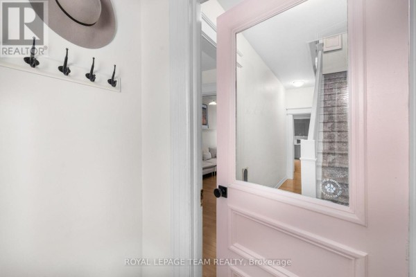 Interior entryway with a light pink door, coat hooks, and a mirror reflecting a hallway. - 275 Arlington Avenue, Ottawa