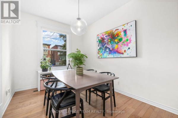 Dining area with a wooden table, black chairs, a window, and colorful abstract art. - 275 Arlington Avenue, Ottawa