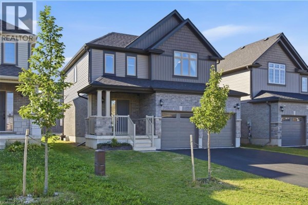 A side exterior view of a two-story house with gray siding, stone accents, and a double garage. - 275 Bradshaw Drive, Stratford