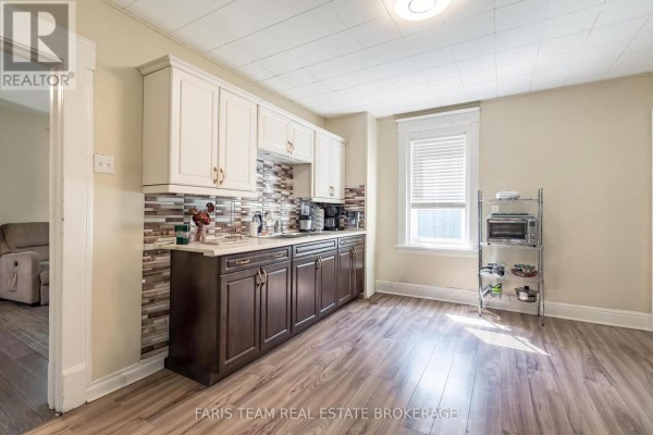 Kitchen with dark brown and white cabinets, a mosaic tile backsplash, and laminate flooring. - 275 Gill Street, Orillia