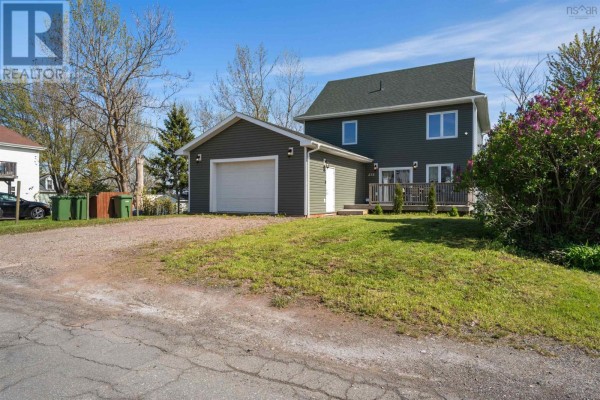 Open-concept basement living area with wood laminate flooring and a ping pong table. - 275 High Street, Pictou