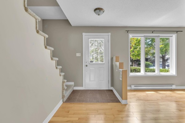 Interior view of a hallway with a staircase, front door, and a large window overlooking trees. - 275 Rue A.-primeau, Gatineau