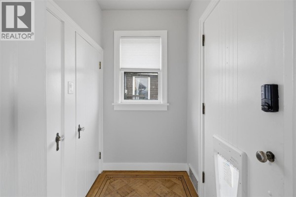 Interior hallway with light gray walls, white doors on either side, a small window, and a parquet floor. - 275 Seymour  W Street, Kamloops