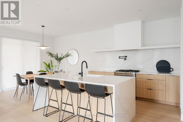 Kitchen island with bar stools and view of stainless steel gas range. - 275 Silver Maple Circle, Thames Centre