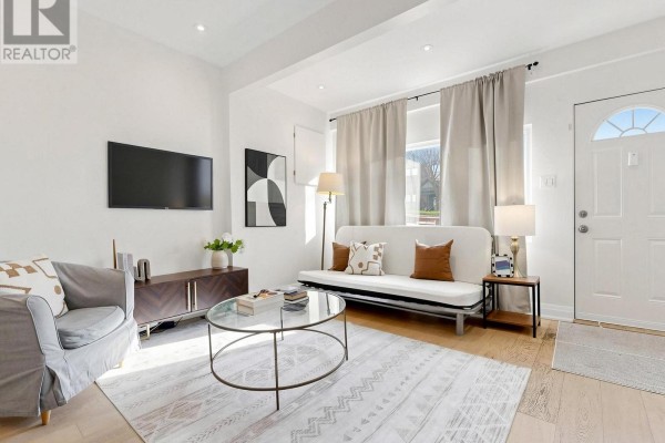 Living room with sofa, futon, coffee table, rug, and front door. - 275 Victoria Park Avenue, Toronto