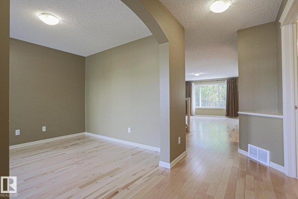 Foyer with a white door, striped rug, beige walls, and a window with a view of the porch. - 2750 Miles Pl Sw Sw, Edmonton