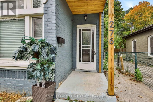 Front exterior of a blue brick house with a white bay window and a porch. - 276 Dalhousie Street, Brantford