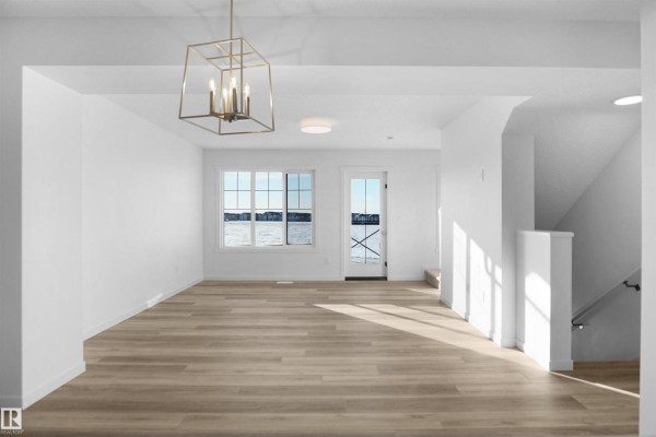 Living room with light wood floors, white walls, and a view of the water through windows. - 276 Deer Valley Dr, Leduc