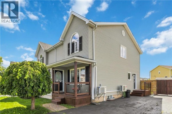Side exterior view of the light grey duplex, showing the dark wood porch and driveway. - 276 Glencairn Drive, Moncton