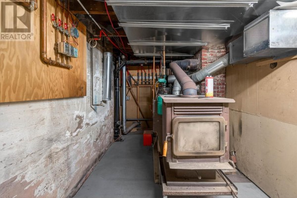 Basement utility area with wood stove, pipes, and electrical panel - 276 South Drive, Summerside