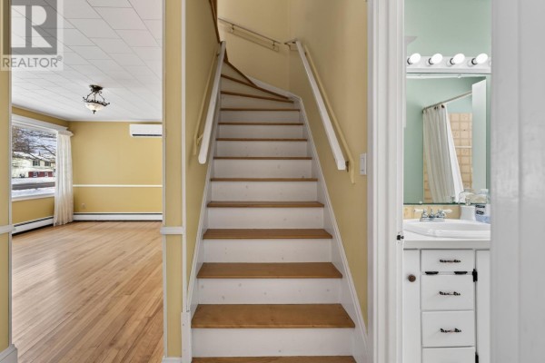 Interior view of a staircase with yellow walls and hardwood floors - 276 South Drive, Summerside