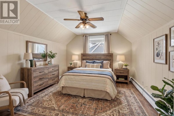 Bedroom with a king-sized bed, wooden dresser, and patterned rug - 276 South Drive, Summerside