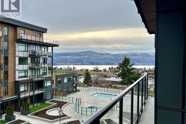 View from a balcony of an apartment complex with a pool and distant mountains. - 2760 Olalla Road Unit# 407, West Kelowna