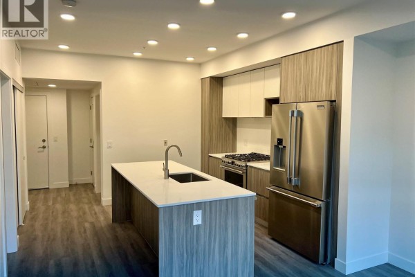Modern kitchen with a large island, stainless steel appliances, and two-tone cabinetry. - 2760 Olalla Road Unit# 407, West Kelowna