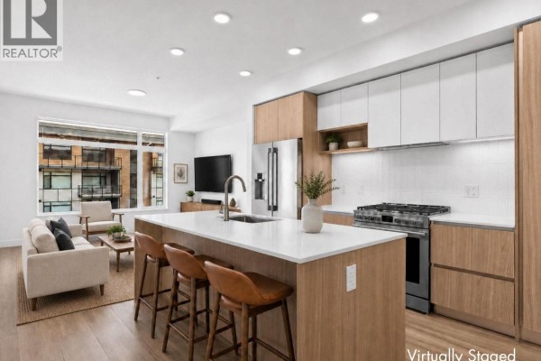 Modern kitchen and living room with white countertops, wood cabinets, and light wood flooring. - 2760 Olalla Road Unit# 506, West Kelowna