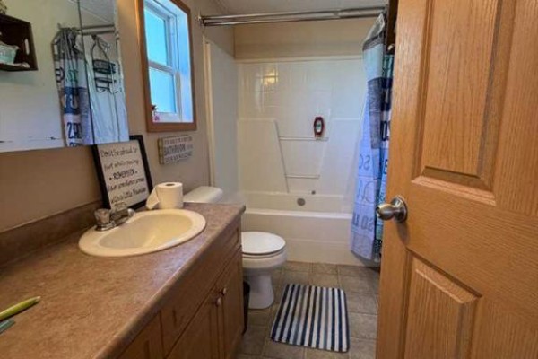 A bathroom with a sink, toilet, bathtub, and shower curtain. - 2761 Bambi Street, Wabasca