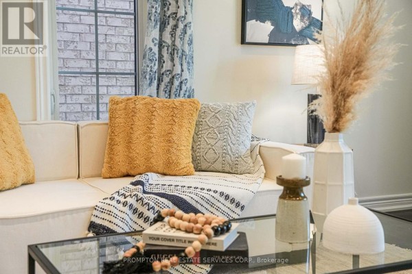 Close-up of a white sofa with yellow and grey textured throw pillows and a patterned blanket. - 2762 Donald Cousens Parkway, Markham