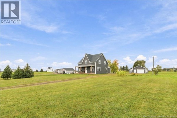 Aerial view of a grey house with a large yard, detached garage, and distant buildings. - 2764 Route 515, Sainte Marie De Kent