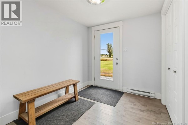 Interior entryway with light grey walls, wooden bench, two mats, and a glass-paneled door. - 2764 Route 515, Sainte Marie De Kent