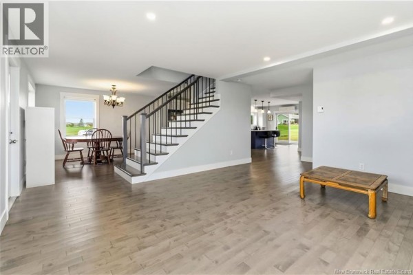 Living and dining area with light grey walls, wood floors, staircase, dining table, and furniture. - 2764 Route 515, Sainte Marie De Kent