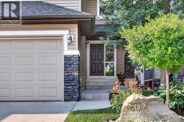 Close-up of the front door and garage of a house, with stone accents and flowers. - 277 Evermeadow Avenue Sw, Calgary