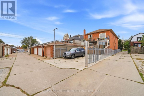 Backyard view of the property with a driveway, garages, and fenced yard. - 277 Harvie Avenue, Toronto